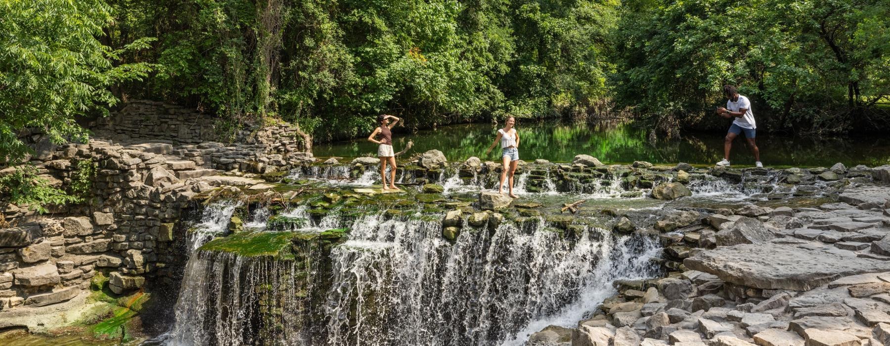 people standing on a rock bridge over a river